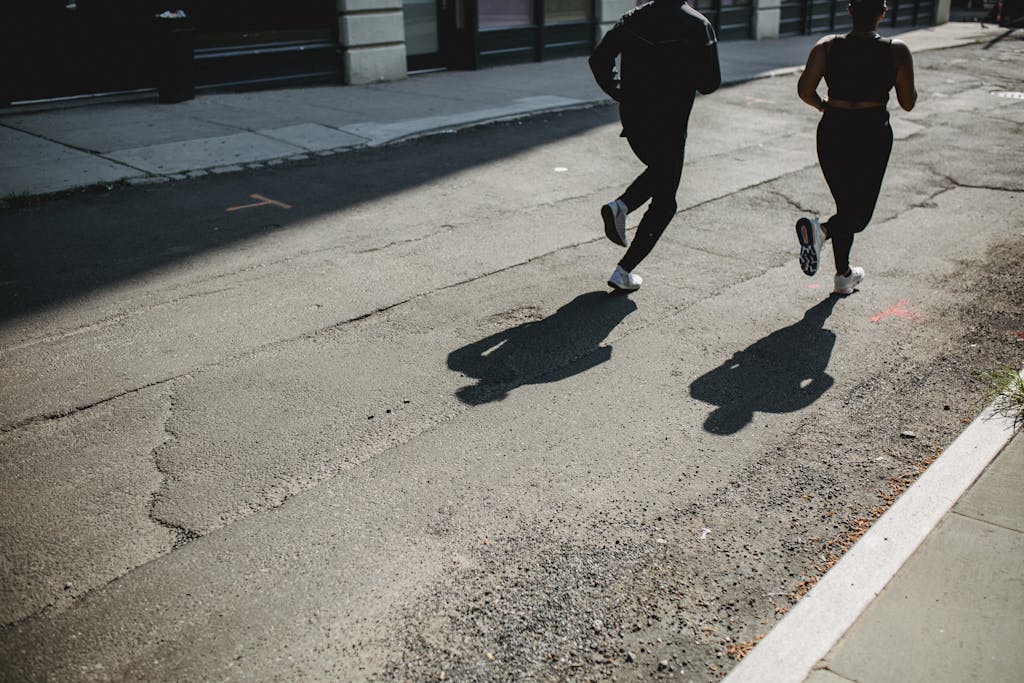 Silhouetted joggers run along a city street, capturing movement and urban fitness.